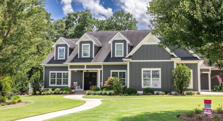 A large gray new house with a landscaped yard and leading pathway sidewalk.